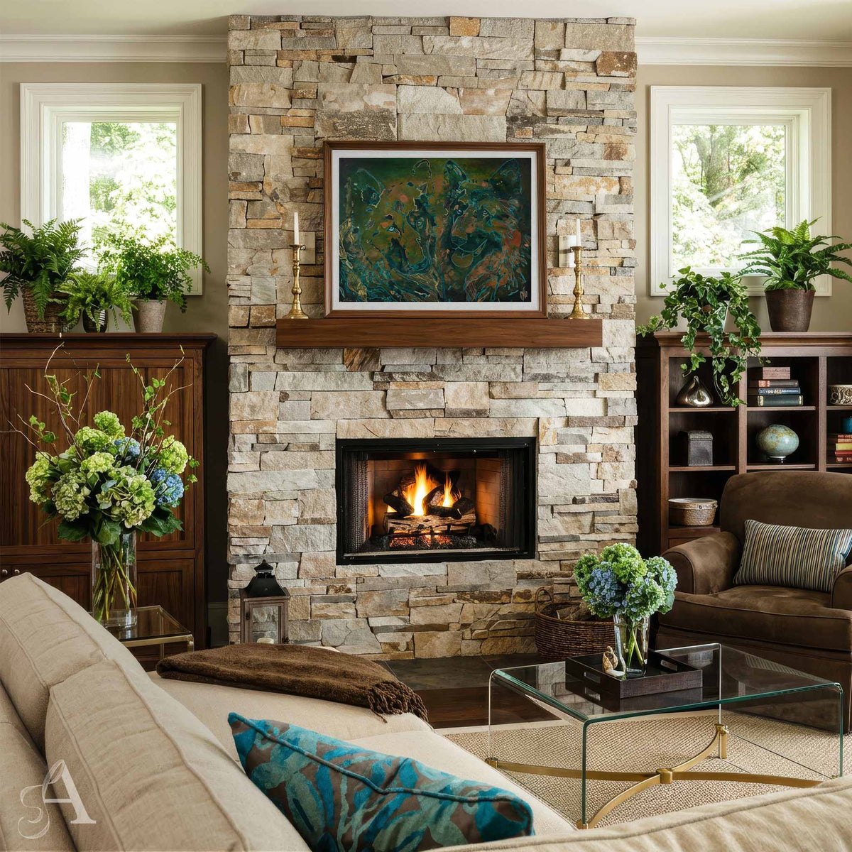 A styled living room featuring a large stone fireplace with a wood mantel and a framed abstract German Shepherd Dog painting above it. A lit fire burns in the fireplace insert.