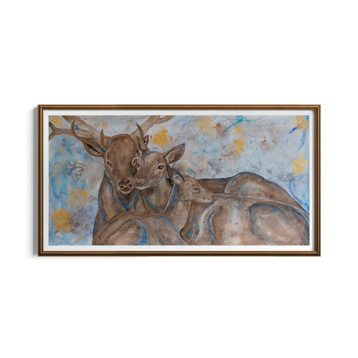 A framed watercolor painting of a mother and father deer and their fawn resting together, featuring soft blue and brown tones with subtle gold accents, set in a white mat and a warm brown wooden frame.